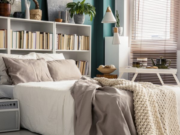 Creative use of small space in a stylish bedroom interior with designer decor and cozy white and beige bedding