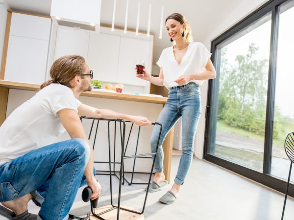 Young couple doing house chores assembling chair and cooking at the kitchen of the modern apartment
